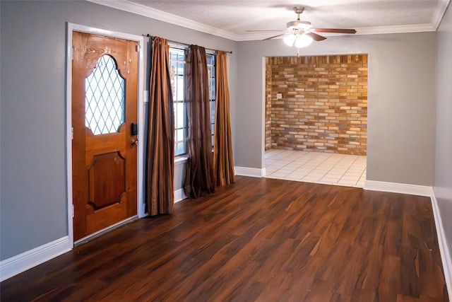 entryway with ornamental molding, wood finished floors, a ceiling fan, and baseboards