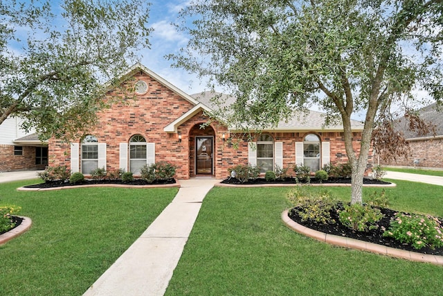 view of front of house featuring roof with shingles, a front lawn, and brick siding