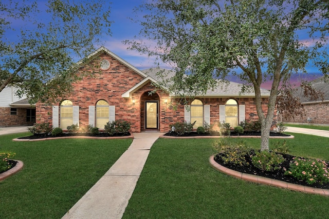 ranch-style house featuring a shingled roof, a front lawn, and brick siding