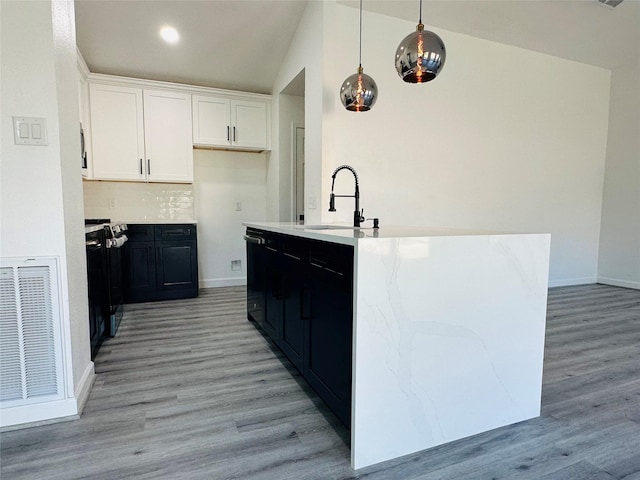 kitchen featuring pendant lighting, visible vents, white cabinets, light wood-type flooring, and dark cabinetry