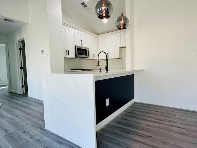 kitchen featuring white cabinetry, visible vents, stainless steel microwave, and wood finished floors