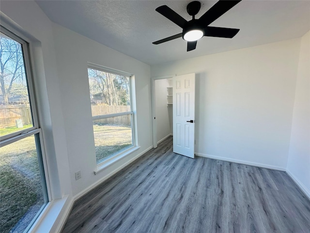 spare room featuring a ceiling fan, a textured ceiling, baseboards, and wood finished floors