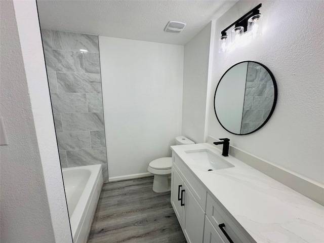 full bath with visible vents, toilet, vanity, a textured ceiling, and wood finished floors