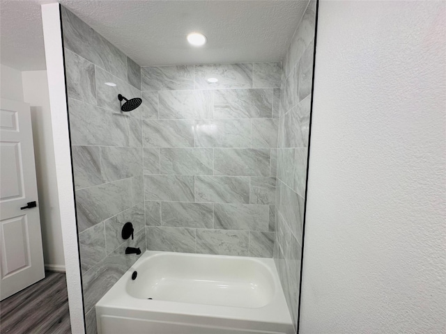 full bath featuring shower / washtub combination, a textured wall, a textured ceiling, and wood finished floors