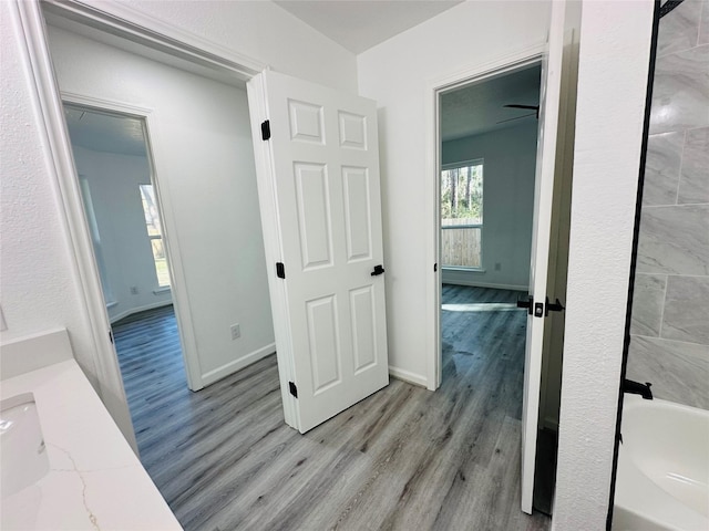 full bath with a tub to relax in, baseboards, and wood finished floors