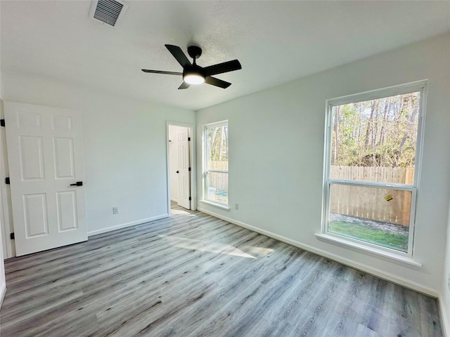 unfurnished bedroom with visible vents, ceiling fan, baseboards, and wood finished floors