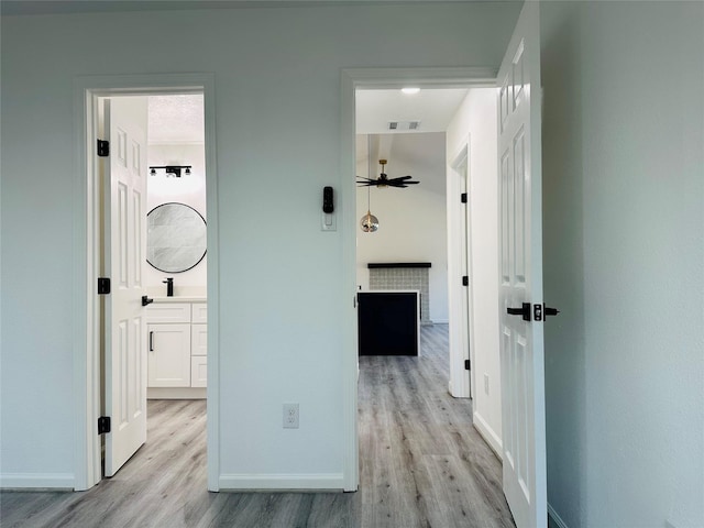 hall featuring visible vents, baseboards, and wood finished floors