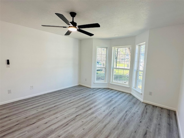 spare room featuring a textured ceiling, ceiling fan, wood finished floors, and baseboards