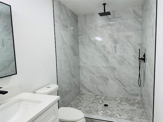 bathroom featuring tiled shower, vanity, and toilet