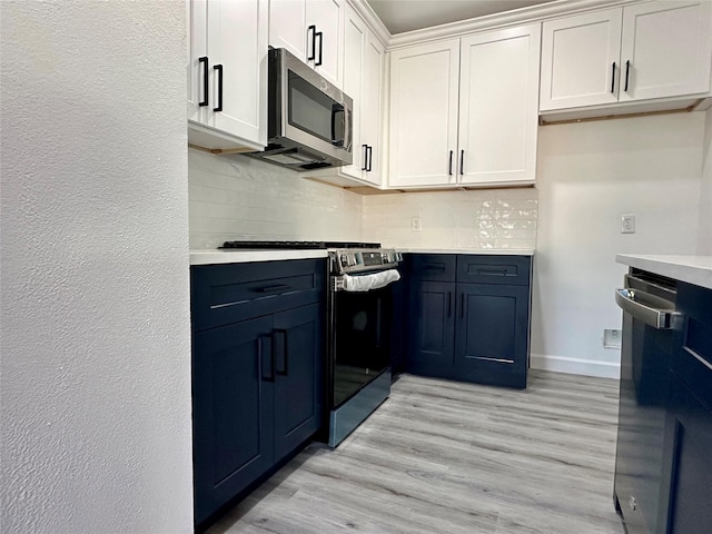 kitchen with stainless steel appliances, white cabinets, light countertops, decorative backsplash, and light wood finished floors