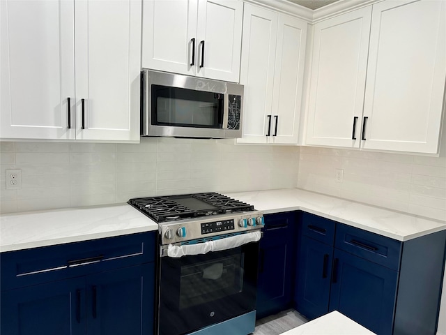 kitchen with light stone counters, blue cabinetry, stainless steel appliances, decorative backsplash, and white cabinets