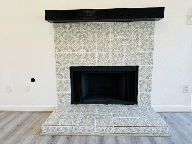 details with a tile fireplace, baseboards, and wood finished floors