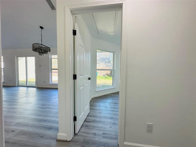 hall with visible vents, wood finished floors, attic access, and baseboards