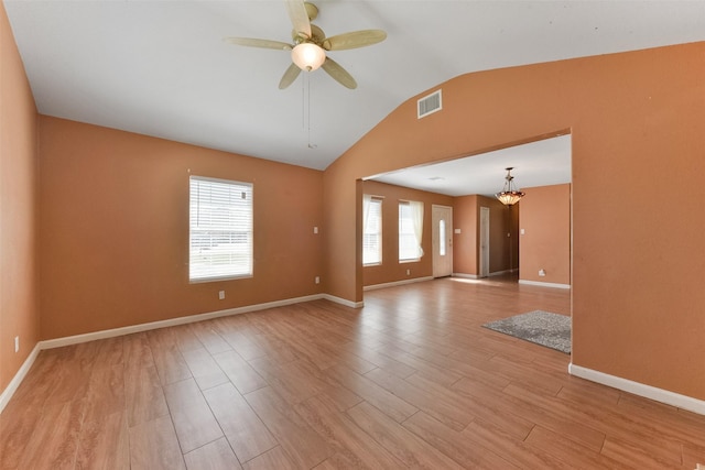 spare room with baseboards, visible vents, lofted ceiling, ceiling fan with notable chandelier, and light wood-type flooring