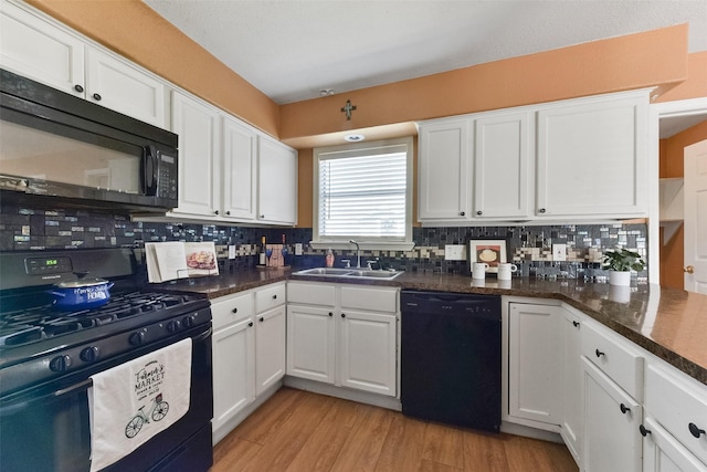 kitchen with black appliances, a sink, backsplash, white cabinetry, and light wood-style floors