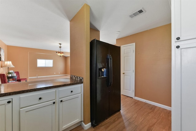 kitchen featuring visible vents, white cabinets, light wood-style floors, dark countertops, and black fridge