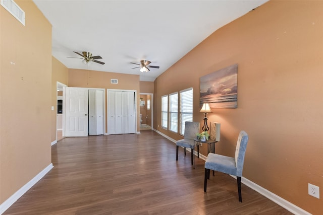 sitting room featuring wood finished floors, baseboards, visible vents, and vaulted ceiling