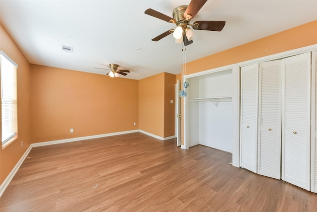 unfurnished bedroom with a ceiling fan, light wood-style floors, multiple closets, and baseboards