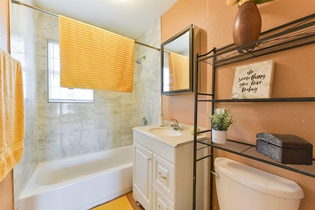 bathroom featuring a textured wall, bathing tub / shower combination, vanity, and toilet