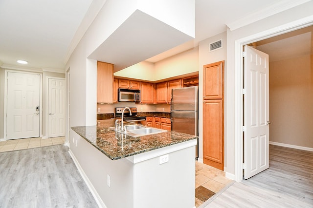 kitchen featuring stainless steel appliances, visible vents, ornamental molding, a sink, and a peninsula