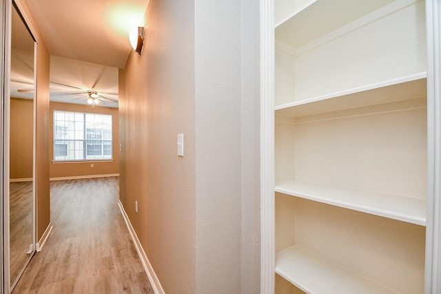 corridor with baseboards and wood finished floors