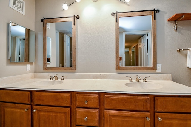 bathroom featuring double vanity, a sink, and visible vents