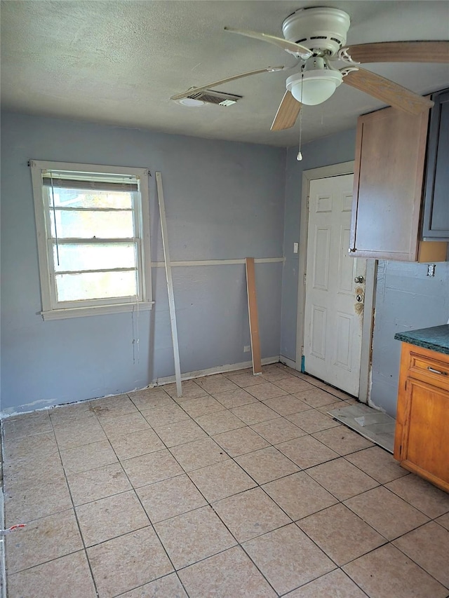 interior space with a textured ceiling, visible vents, and a ceiling fan