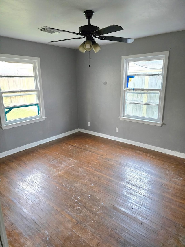 unfurnished room with wood-type flooring, visible vents, baseboards, and a ceiling fan