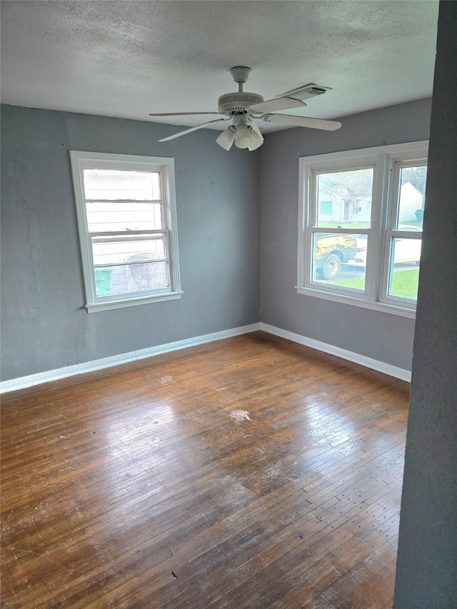 empty room with hardwood / wood-style flooring, ceiling fan, baseboards, and a textured ceiling