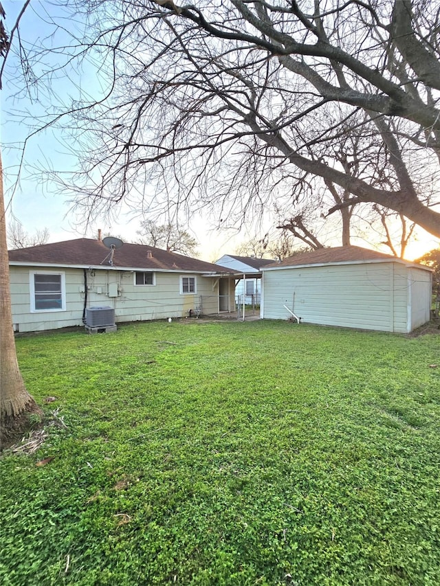 back of property featuring an outbuilding, central AC unit, and a lawn