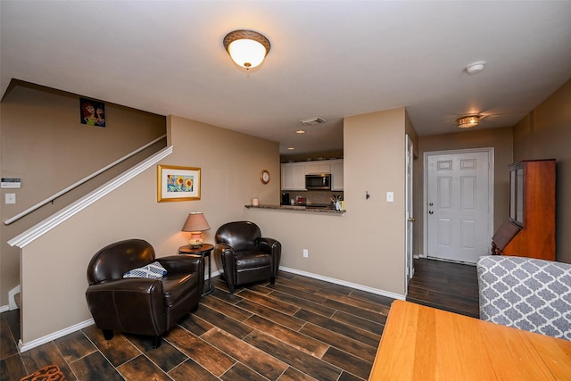 living area featuring wood finish floors, visible vents, stairway, and baseboards