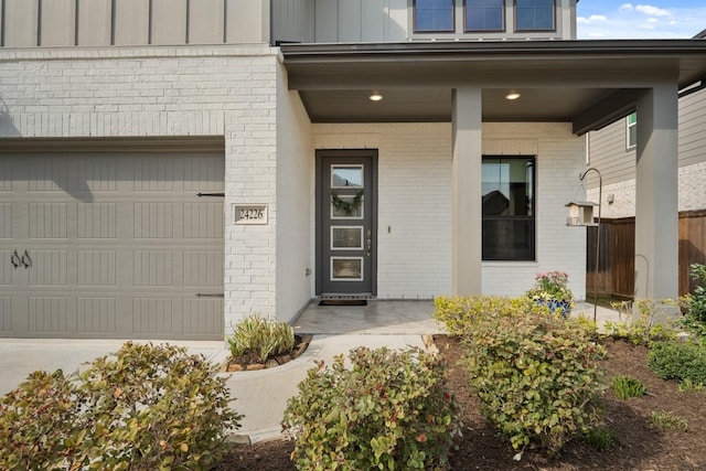 view of exterior entry featuring board and batten siding, brick siding, a porch, and an attached garage