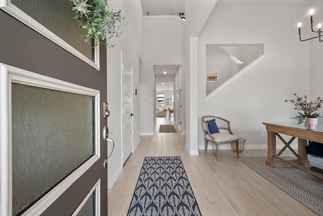 entrance foyer with light wood finished floors, stairs, baseboards, and a notable chandelier