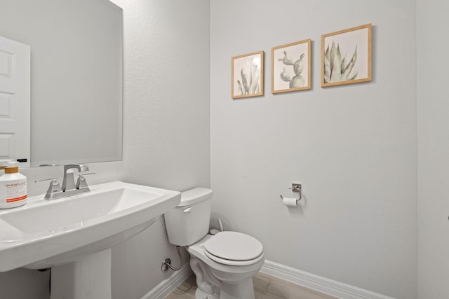 bathroom featuring a sink, toilet, and baseboards