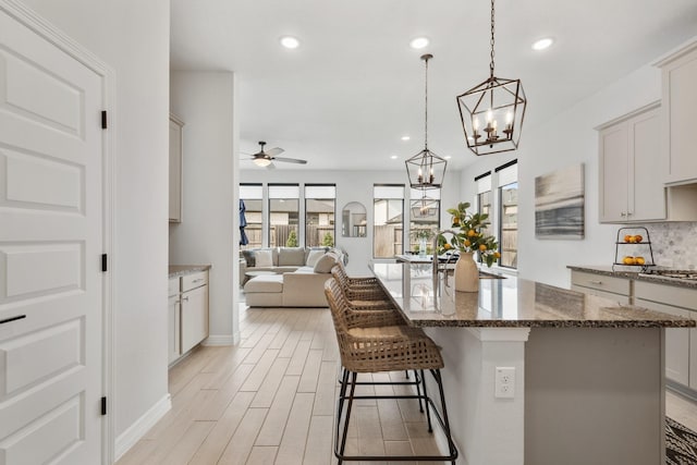 kitchen with stainless steel gas cooktop, open floor plan, a sink, and light wood-style floors