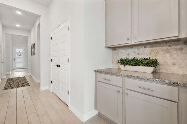 kitchen with light wood finished floors, tasteful backsplash, and light stone counters