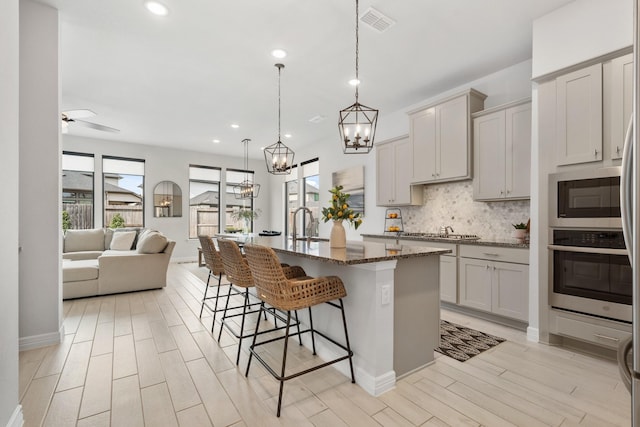 kitchen with tasteful backsplash, visible vents, open floor plan, a kitchen breakfast bar, and stainless steel appliances