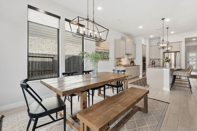 dining room featuring baseboards, light wood-style floors, recessed lighting, and an inviting chandelier