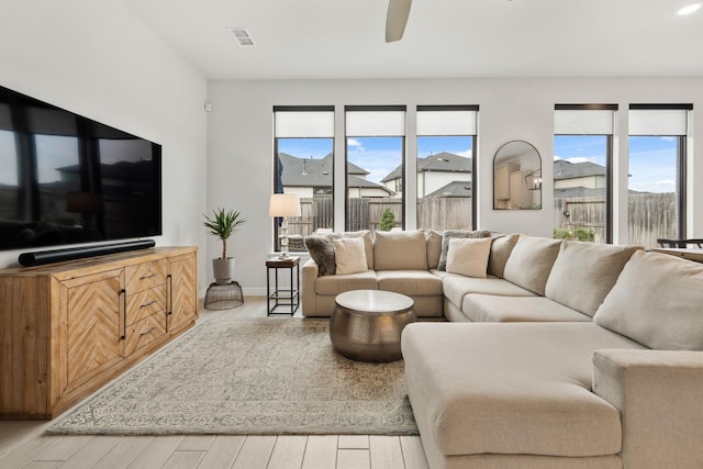 living room with visible vents, ceiling fan, baseboards, and wood finished floors