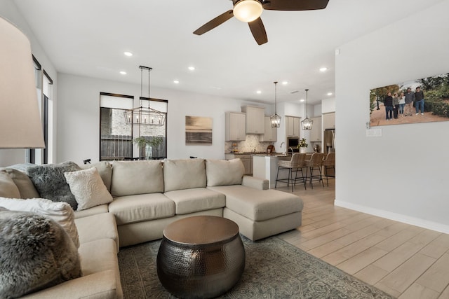 living area featuring light wood-style floors, baseboards, a ceiling fan, and recessed lighting