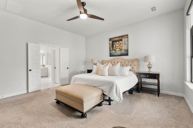 bedroom with light colored carpet, ensuite bath, visible vents, and baseboards