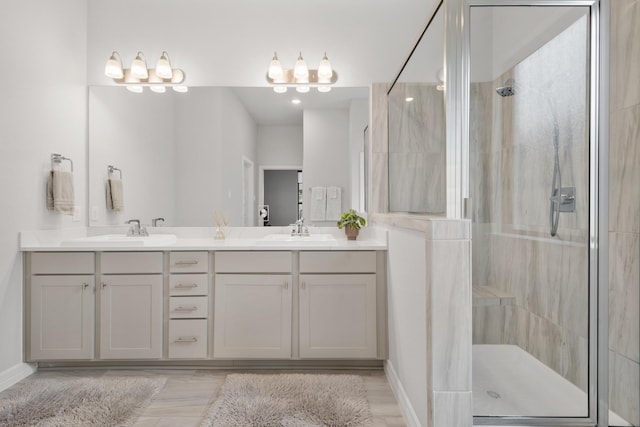 full bathroom with a sink, a shower stall, baseboards, and double vanity