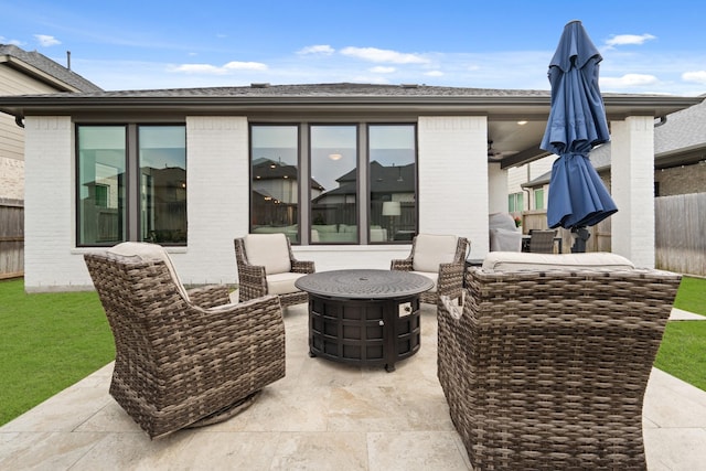 view of patio with an outdoor fire pit, fence, and ceiling fan