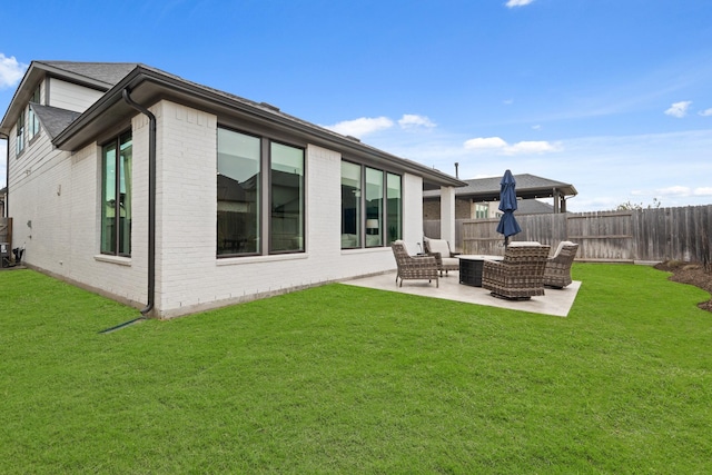 rear view of house with a yard, a patio, brick siding, and fence