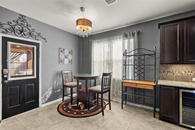 dining space featuring light tile patterned flooring, a notable chandelier, beverage cooler, visible vents, and baseboards