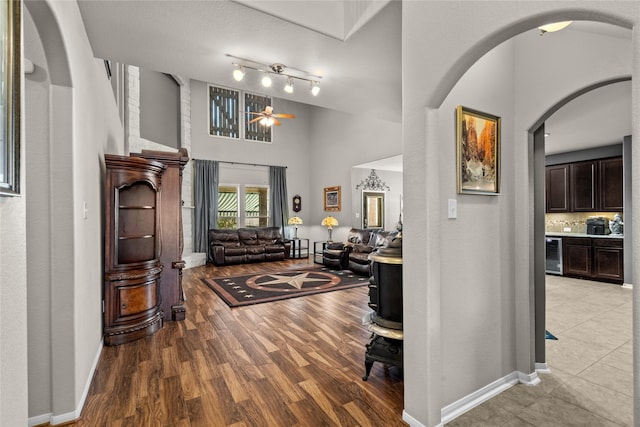 entrance foyer featuring light wood-type flooring, beverage cooler, a towering ceiling, and baseboards