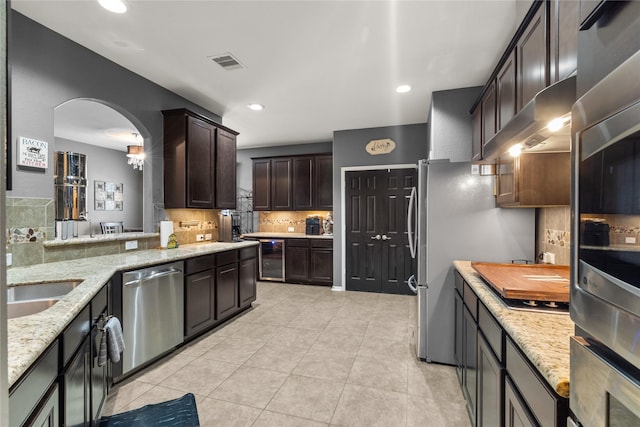 kitchen with wine cooler, stainless steel appliances, visible vents, decorative backsplash, and dark brown cabinetry