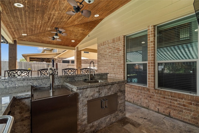 view of patio / terrace featuring exterior kitchen, a sink, a ceiling fan, and fence