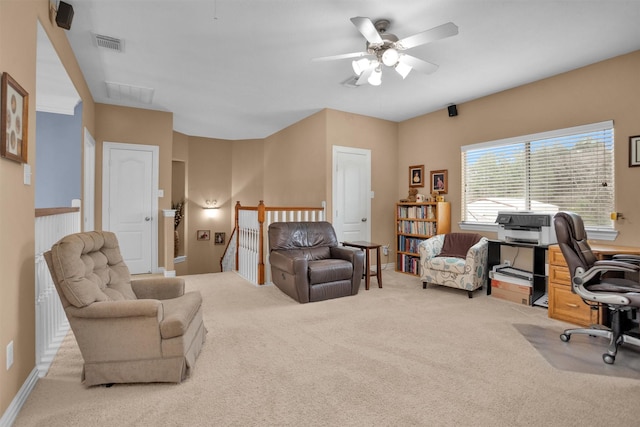 office space with visible vents, light carpet, baseboards, and a ceiling fan