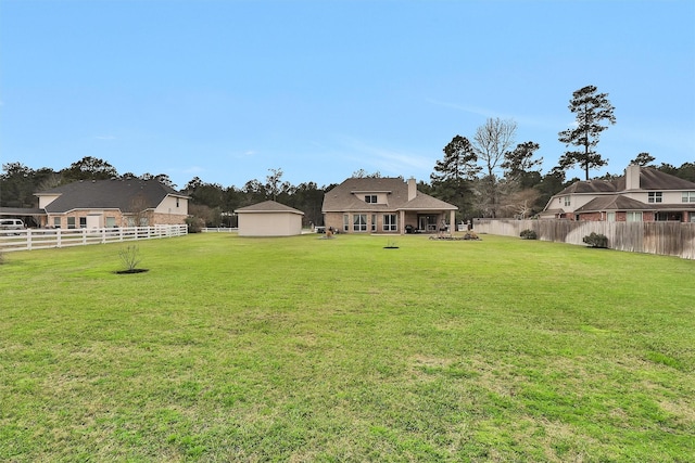 view of yard featuring a storage unit, an outbuilding, and a fenced backyard